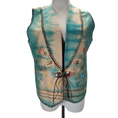 a white mannequin wearing a blue vest with floral designs on the front and back