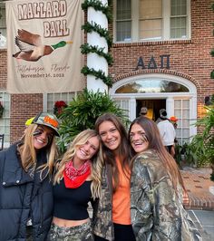 three beautiful women standing next to each other in front of a building