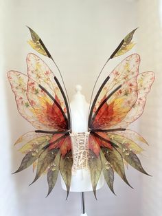 a white mannequin headdress with multicolored leaves on it's wings