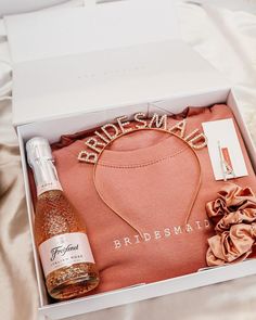 a bridesmaid gift box with a bottle of champagne and a necklace in it