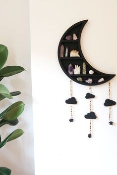 a crescent shaped shelf with beads hanging from it's sides next to a potted plant