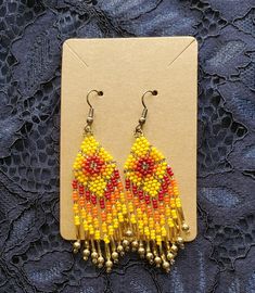 a pair of yellow and red beaded earrings sitting on top of a piece of paper