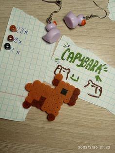 two pieces of crafting paper on top of a wooden table with earring clips