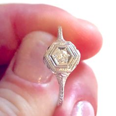 a close up of a person's hand holding a ring with a diamond in it