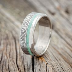 a wedding ring with an intricate design on the inside is sitting on a piece of wood