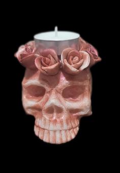 a candle that is in the shape of a skull with two roses on its head