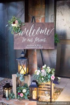 a welcome sign with flowers and lanterns on the ground