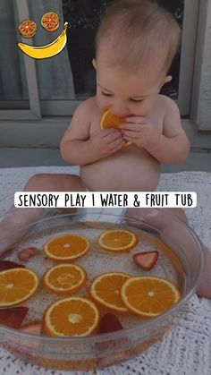 a baby sitting in front of a bowl of oranges with the words sensory play i water & fruit tub