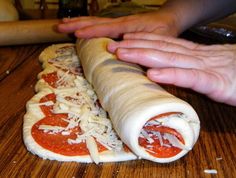 someone is making a pizza roll with cheese and tomato sauce on the top, while another person holds out their hand over it