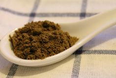 a spoon filled with brown powder on top of a checkered table cloth