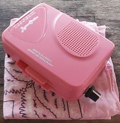 a pink portable radio sitting on top of a wooden table next to a white towel