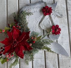 a christmas wreath with poinsettis and greenery on a white wooden background