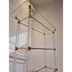 a glass shelf with brass fittings on the bottom and sides, against a white wall