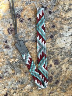 a red and white beaded lanyard sitting on top of a granite countertop