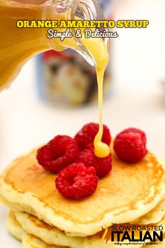 a person pouring syrup on top of a pancake with raspberries