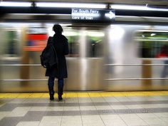 a person standing on a subway platform waiting for the train to come in and out