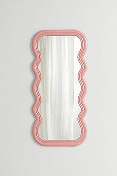 a pink scalloped mirror on a white wall