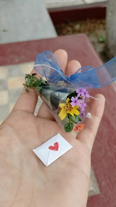 a person holding flowers in their hand with a heart sticker on the tip of it