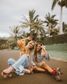 three women sitting on the ground with their skateboards in front of them and palm trees behind them