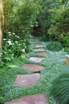 a stone path surrounded by green grass and flowers