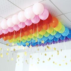 a bunch of balloons hanging from the ceiling in a room with stars and streamers