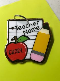 a teacher's name tag with an apple, pencil and eraser on it