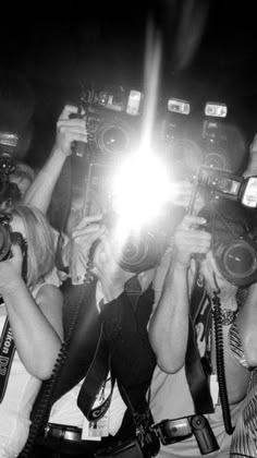 a group of people holding up cameras in front of their faces and taking pictures with them