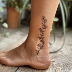 a woman's foot with a flower tattoo on the side of her leg, next to potted plants