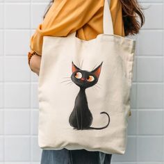 a woman carrying a tote bag with a black cat drawn on it's front