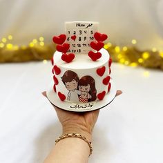 a hand holding a cake with hearts on it and the date is written on top