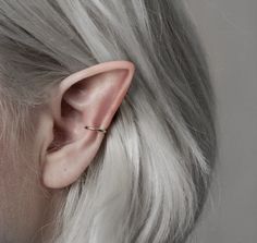 a close up of a person with white hair wearing an ear piercing