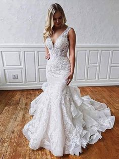 a woman in a white wedding dress standing on a wooden floor next to a wall