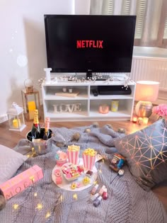 a tv sitting on top of a wooden floor next to a table filled with food