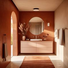 a bathroom with an oval mirror and orange walls