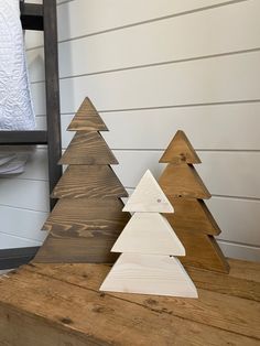 three wooden christmas trees sitting on top of a wooden table next to a bunk bed