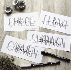 four different types of calligraphy on paper next to some scissors and other writing supplies