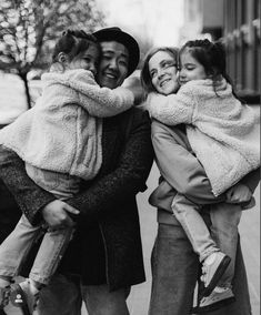 a black and white photo of three people hugging each other while the man is holding two small children