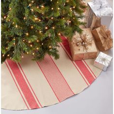 a christmas tree with presents under it on a red and white striped table cloth next to a small fir tree