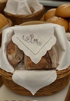 bread in a basket with the word pan on it and some other breads behind it