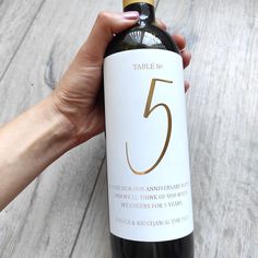 a hand holding a bottle of wine with the number five on it's label