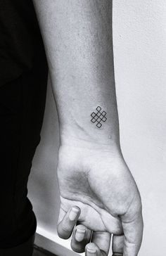 a person with a small tattoo on their left wrist holding the hand of another person