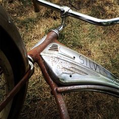 an old rusty bicycle parked in the grass with rust on it's handlebars