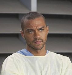 a man with his arms crossed standing in front of some stairs