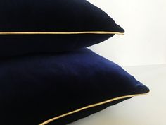 two black pillows with gold piping on them