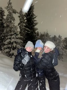 three girls are standing in the snow with their arms around each other