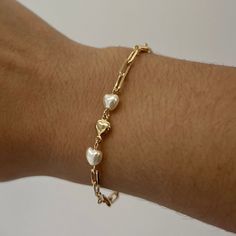 The Lauren Heart Bracelet is a unique symbol of love, style & sophistication. Integrated throughout the bracelet are gold & pearl hearts. The lustrous pearls exude purity and grace, while the gold hearts radiate warmth & timeless beauty. The Lauren Heart Bracelet captures the essence of love & peace. Product Details: 18K Gold-Filled Pearl & Heart Paperclip Bracelet Two Pearl Accents Not Water-Wearable Made in Scottsdale, AZ Heart Paperclip, Paperclip Bracelet, Unique Symbols, Gold Hearts, Pearl Heart, Love And Peace, Gold Bracelets, Solid Gold Jewelry, Symbol Of Love