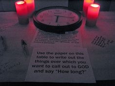 three lit candles are sitting on top of a piece of paper next to a clock