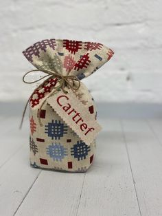 a small bag with a name on it sitting on a white table next to a brick wall