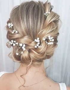 the back of a woman's head with flowers in her hair, wearing a white dress