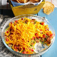 a glass bowl filled with lots of cheese and other food on top of a table